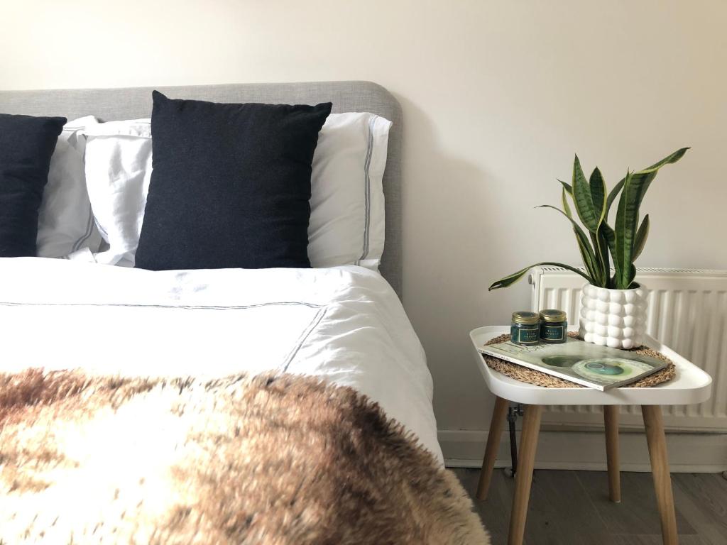 Un dormitorio con una cama y una mesa con una planta en Bright one bedroom apartment in Chiswick, en Londres
