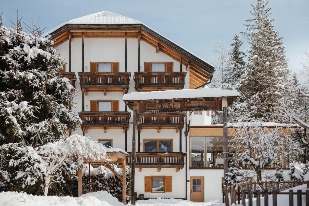 a large house with a balcony in the snow at Hotel Chalet Corso in San Vigilio Di Marebbe