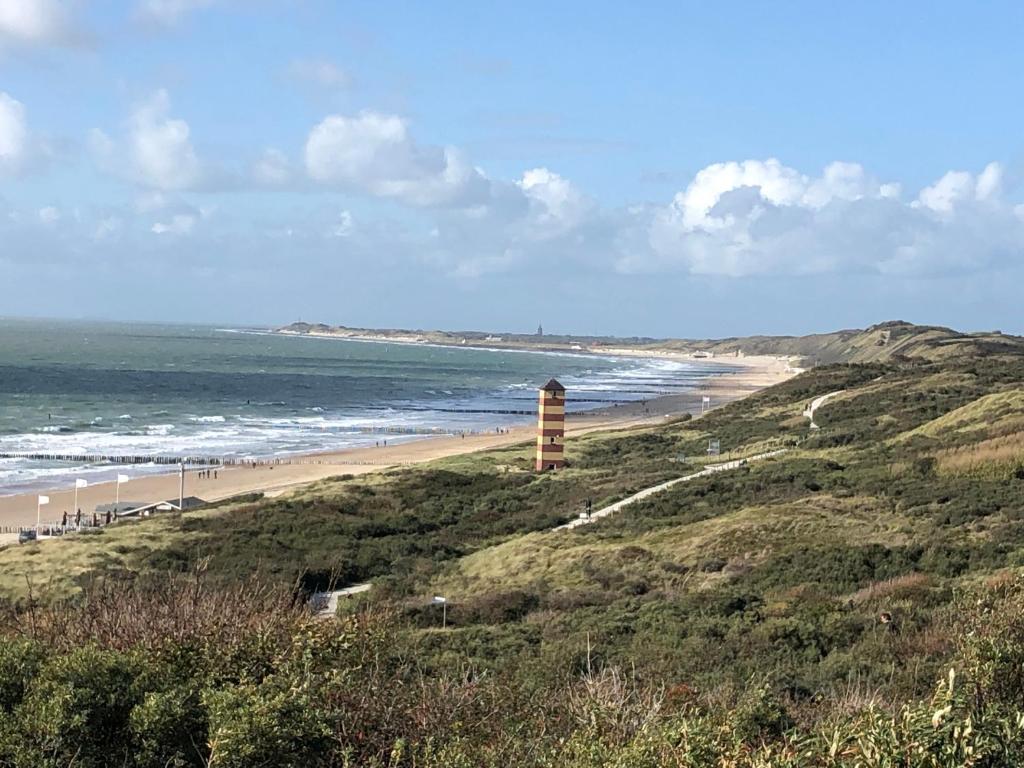 a beach with a lighthouse on a hill next to the ocean at Appartement Dishoek No.46 in Koudekerke