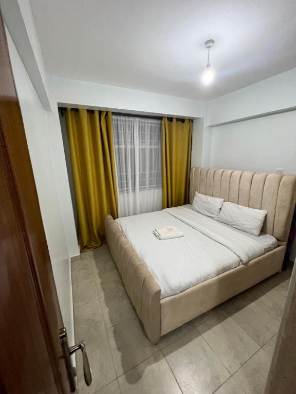 a bedroom with a large bed with yellow curtains at Cossy homes kericho grey point in Kericho