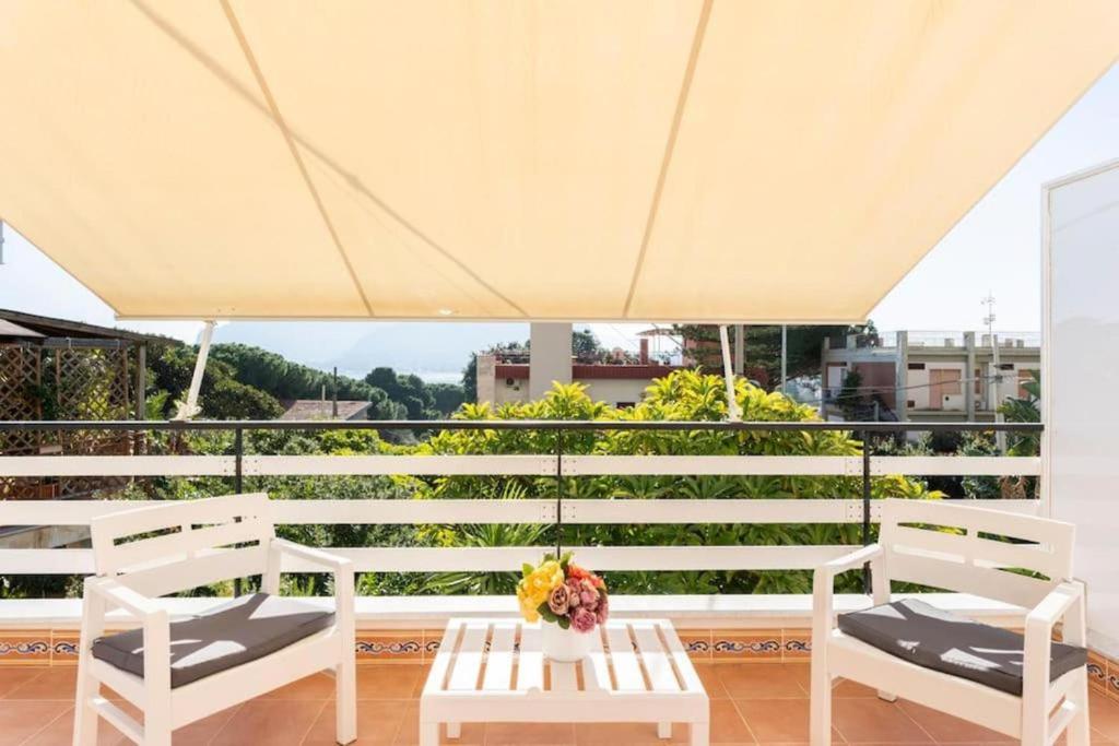 une terrasse avec des chaises blanches et une table fleurie. dans l'établissement Casa Mare me', à Mondello