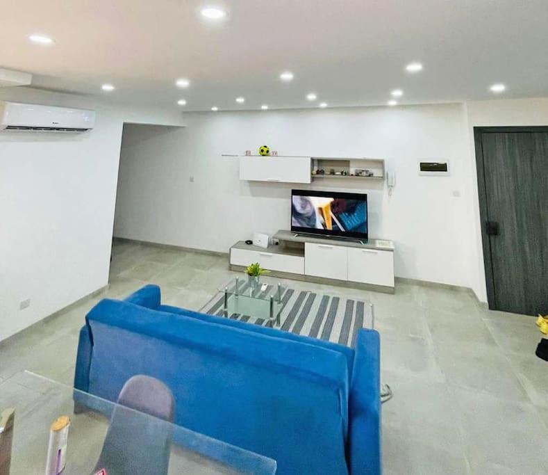 Una sala de estar con un sofá azul y un televisor en Spacious and beautiful flat in Gzira, en Il-Gżira