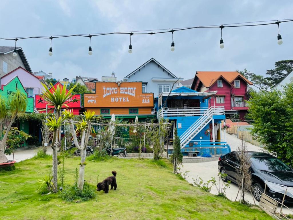 a bear standing on the grass in front of a town at Hometown & Bungalow in Da Lat