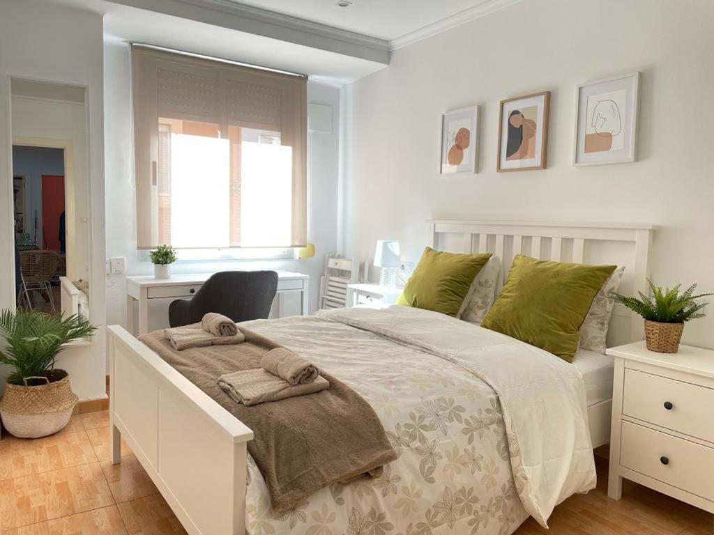 a white bedroom with a large bed with green pillows at UIM Mediterraneo Virgen del Carmen 1 Wifi in Puerto de Sagunto