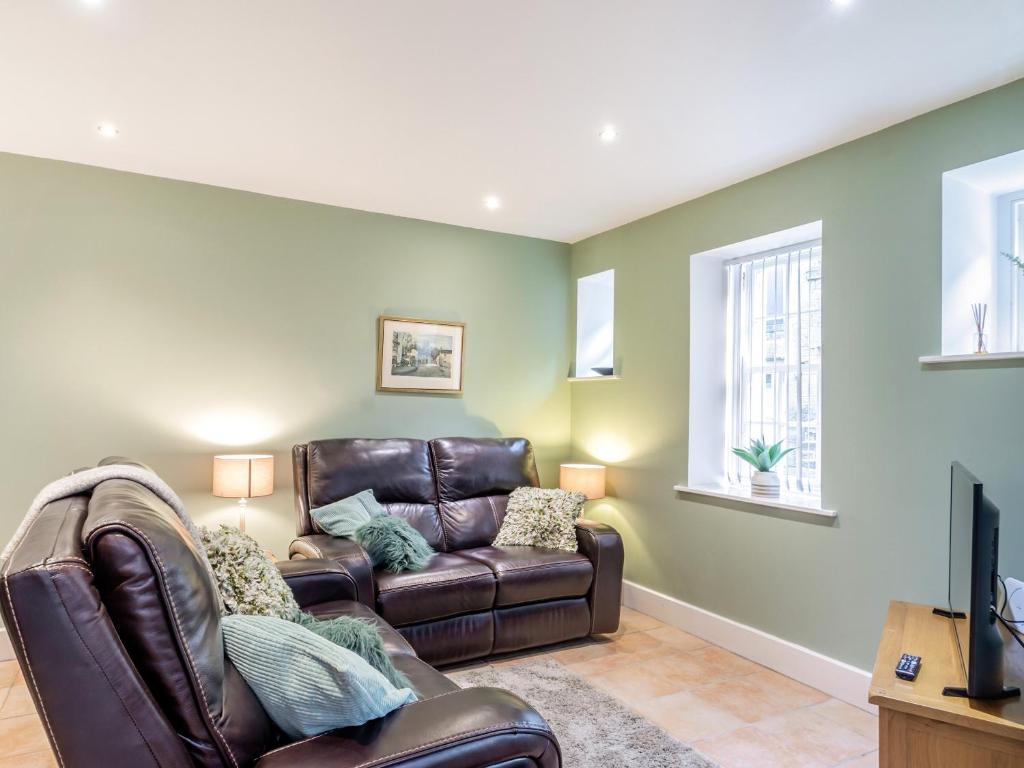 a living room with a leather couch and a television at Riding Cottage - Uk37449 in Pateley Bridge