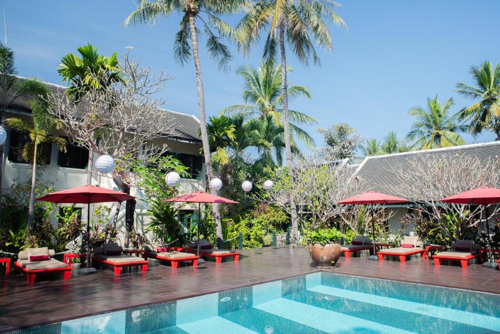 ein Resort mit einem Pool, Tischen und Sonnenschirmen in der Unterkunft Villa Maly Boutique Hotel in Luang Prabang