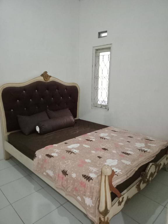 a bedroom with a bed with a floral bedspread and a window at Mutiara Dieng in Wonosobo