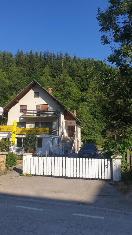 a house with a white fence in front of it at Planinska kuća za odmor Vuković in Podgrab