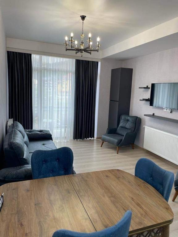 a living room with a table and blue chairs at Didveli Residence Studio Apartment in Bakuriani