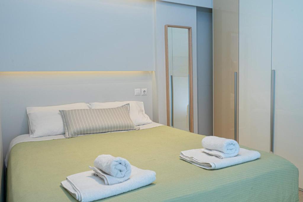 1 dormitorio con 1 cama con toallas y espejo en Nikkis Flat - Kolonaki Square en Athens