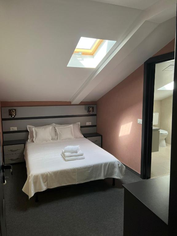 a bedroom with a bed with white sheets and a skylight at Noblesse Bacău in Bacău