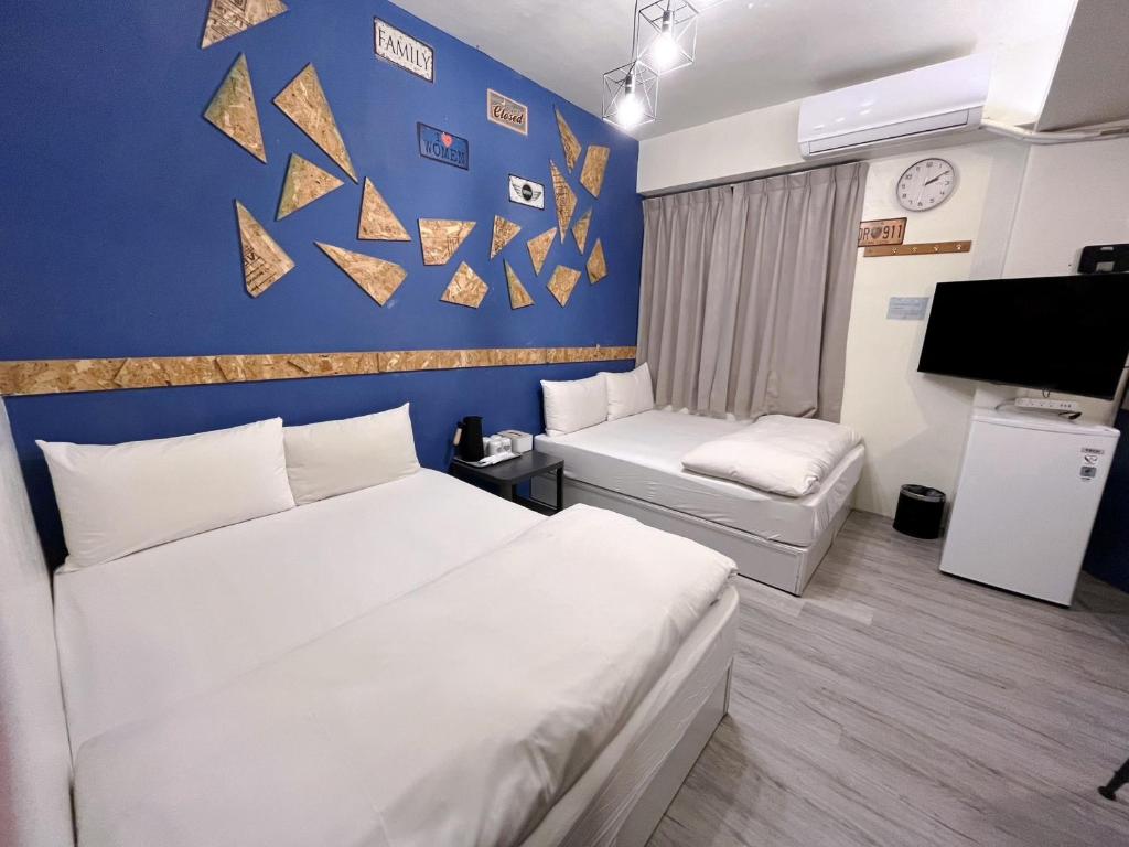 ein Hotelzimmer mit 2 Betten und einer blauen Wand in der Unterkunft FengChia FUN House in Taichung