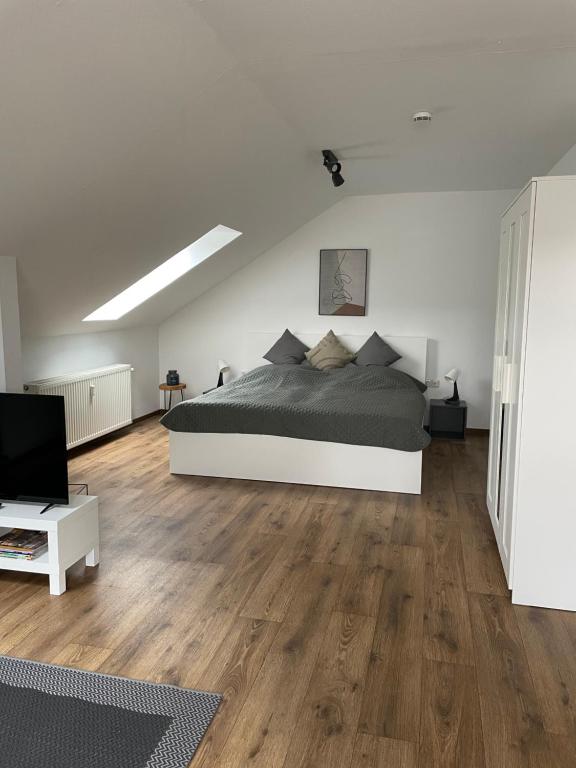 een grote witte slaapkamer met een bed en houten vloeren bij Ferienwohnung Ela in Bad Kissingen