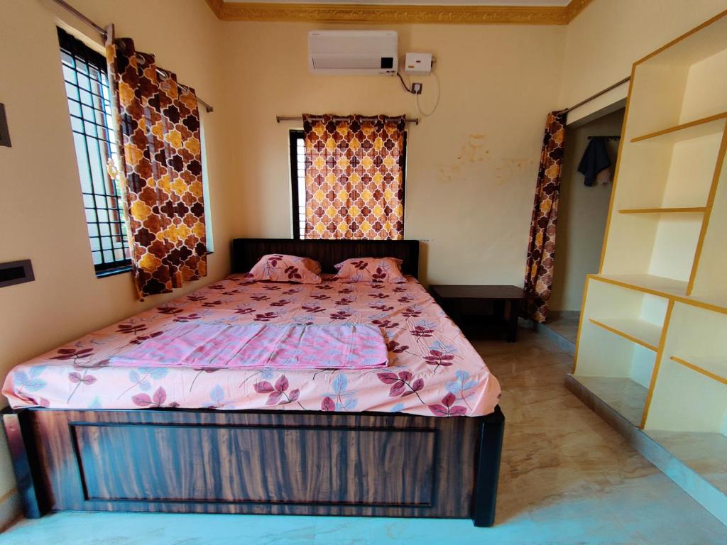 a bedroom with a bed with a pink comforter at Balaji Homestay in Hampi