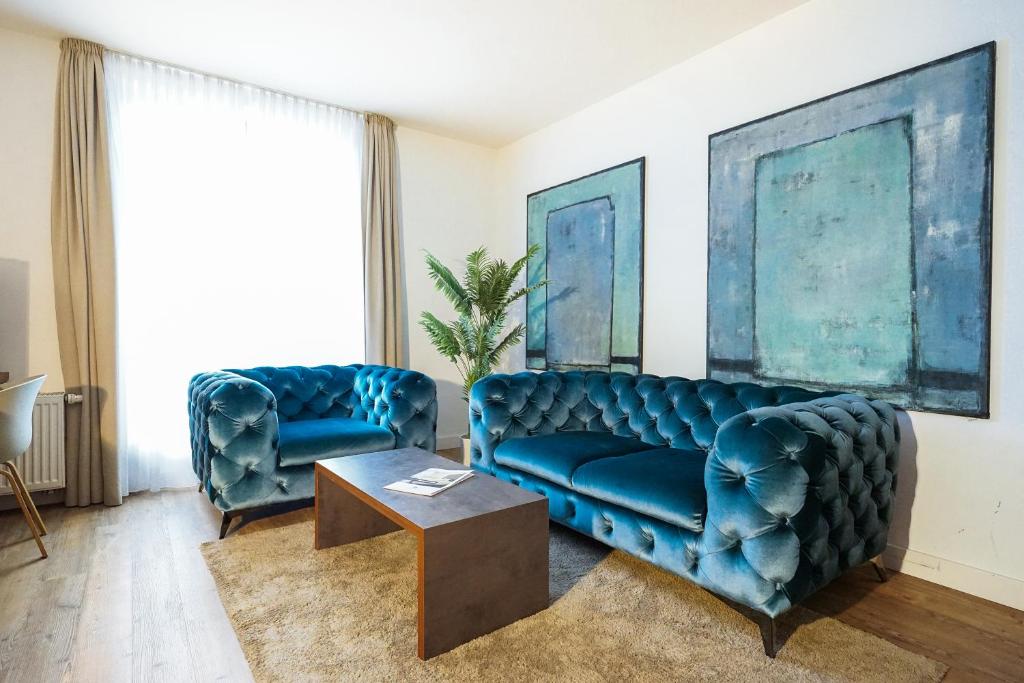 a living room with two blue couches and a table at Hotel Kannenkeller in Lauingen