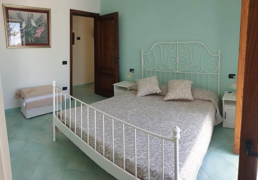 a bedroom with a white bed with a green headboard at La Casetta nel Bosco in Ischia