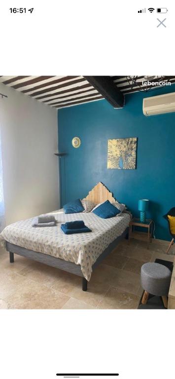 une chambre avec un lit avec un mur bleu dans l'établissement Studio de charme le Clos de l'Etang + place de parking, à LʼIsle-sur-la-Sorgue