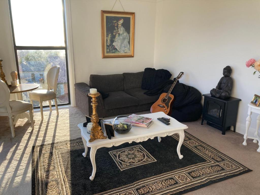 sala de estar con sofá y mesa con guitarra en Hampton’s on Amy, en Burnie