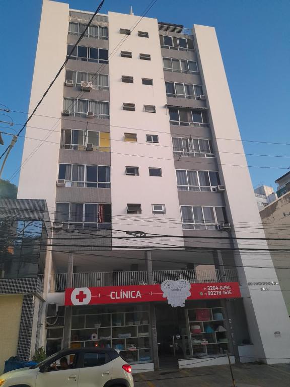 un edificio blanco alto con un coche aparcado delante de él en Apartamento para Carnaval, en Salvador