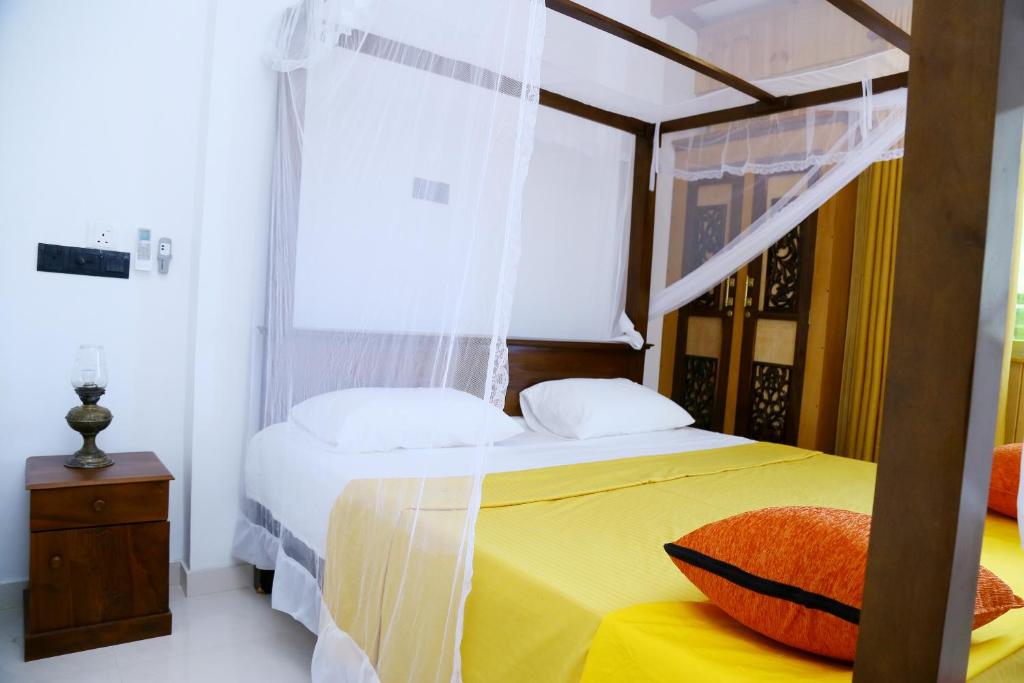 a bedroom with a canopy bed with a yellow blanket at YOUTHENI VILLA in Weligama