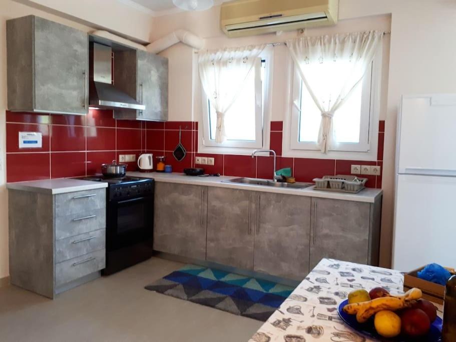 a kitchen with red walls and stainless steel appliances at Dimitra's Apartment in Nydri