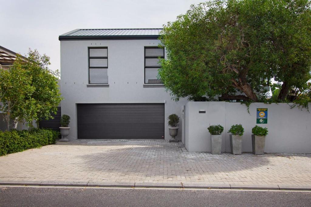 a white house with a garage and a tree at Cozy spacious loft on 4th Avenue in Cape Town