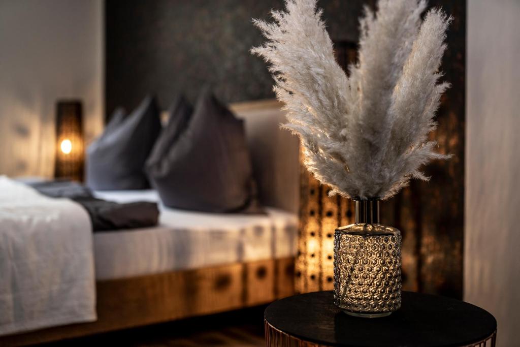 a vase with feathers on a table in a bedroom at das Dietmanns in Bad Tölz