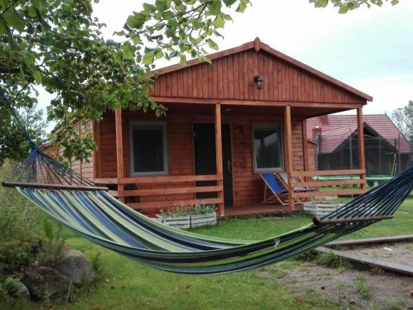 a hammock in front of a log cabin at Przystanek Wakacje in Mikołajki