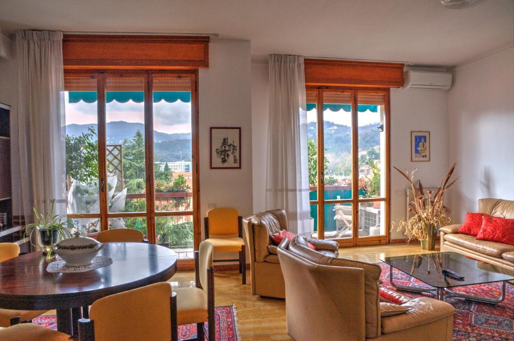 Una sala de estar con mesa y sillas y ventanas. en La Casa di Nilde, en La Spezia
