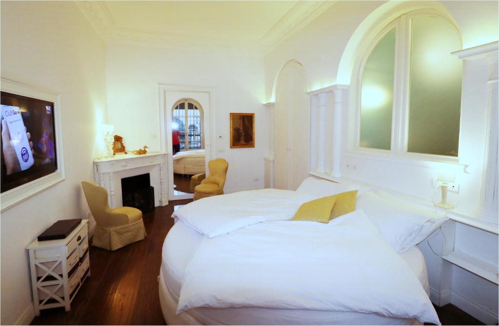 a white bedroom with a bed and a fireplace at Secret Garden Villa Borghese in Rome