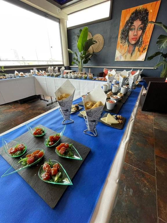 a long blue table with plates of food on it at Hotel Spa Cádiz Plaza in Cádiz