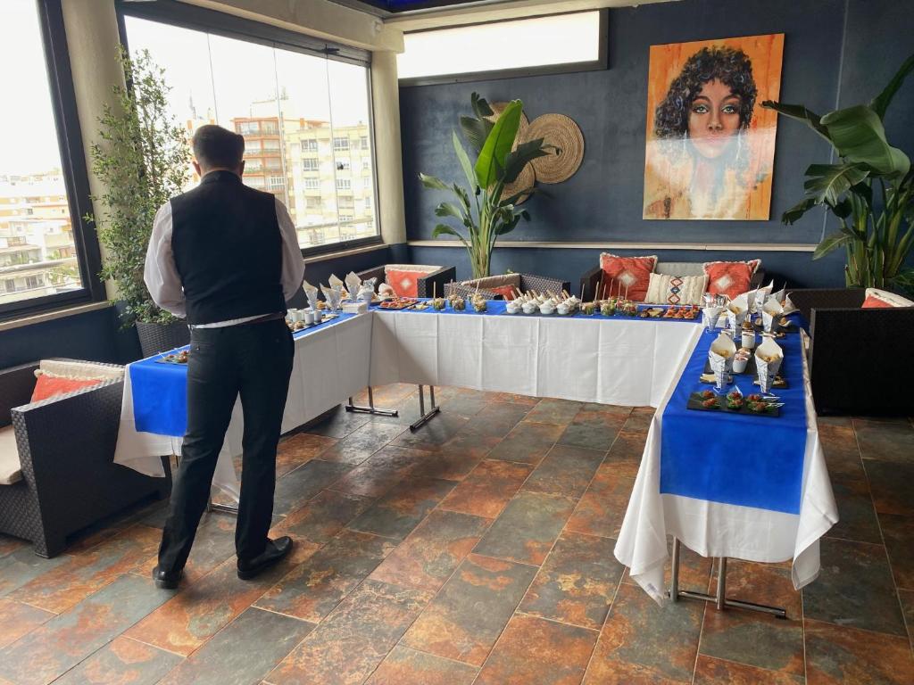a man standing in front of a table with food at Hotel Spa Cádiz Plaza in Cádiz