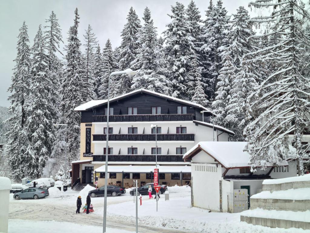 un grande edificio nella neve con gli alberi di Manor Ski Hotel a Predeal