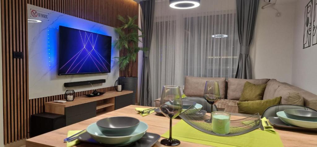 ein Wohnzimmer mit einem Tisch und einem TV in der Unterkunft Luxury Green & Modern Apartment in Skopje