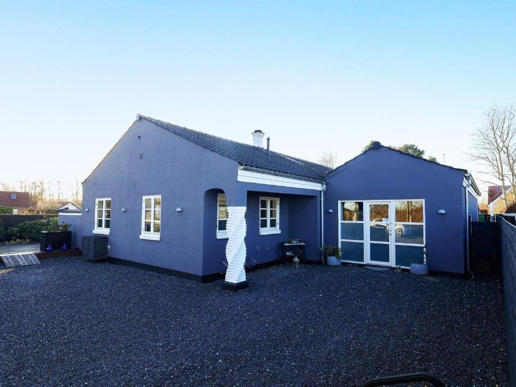 une maison bleue avec une personne debout à l'extérieur dans l'établissement Holiday home Ålbæk LXXXVI, à Ålbæk