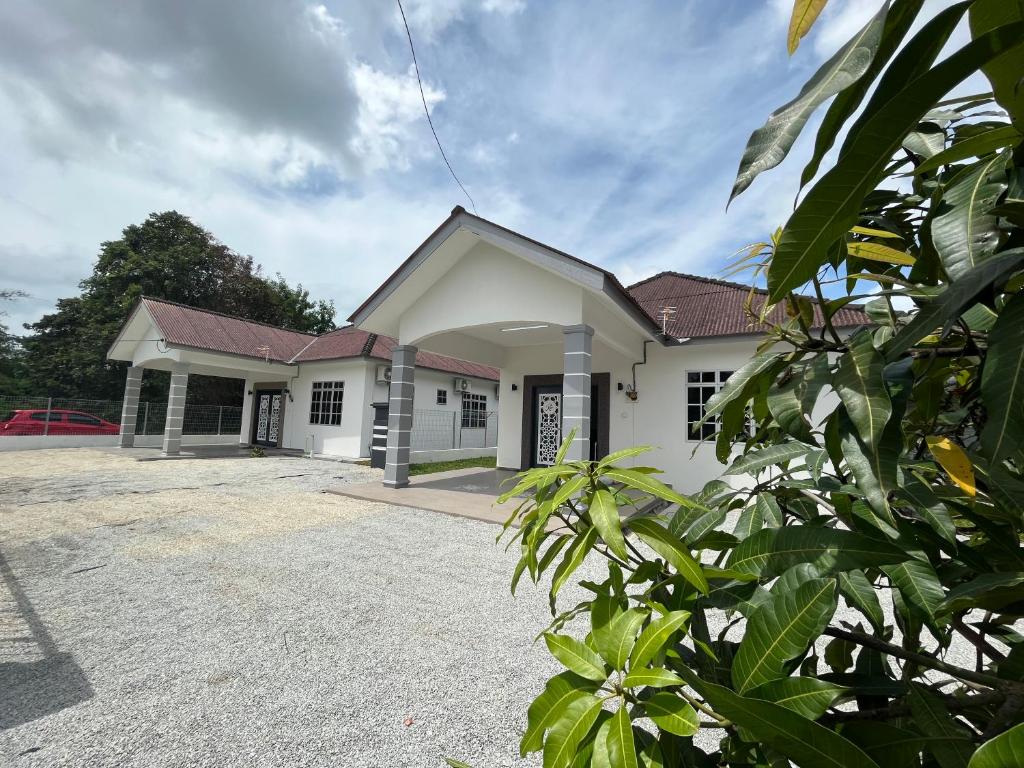 Uma casa branca com uma entrada à frente. em Rumah Tamu Zeha Muar Johor em Muar