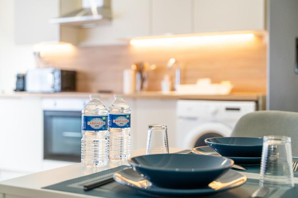 einen Tisch mit zwei Schüsseln und Flaschen Wasser darauf in der Unterkunft **Le Classique** - Appartement 40m² à 500m de la Place d'Armes de Douai in Douai