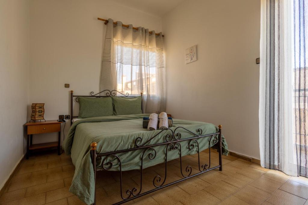 a bedroom with a bed with green sheets and a window at Superior apartment LA in Larisa