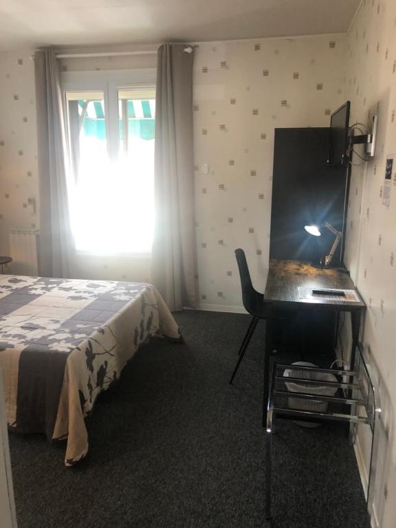 a bedroom with a bed and a desk and a window at Hôtel Le Relais in Fleurance