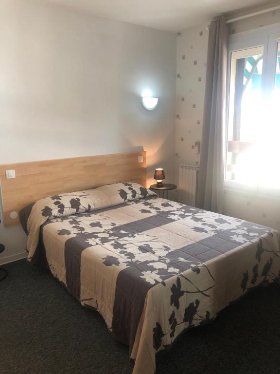 a bedroom with a bed with a black and white blanket at Hôtel Le Relais in Fleurance