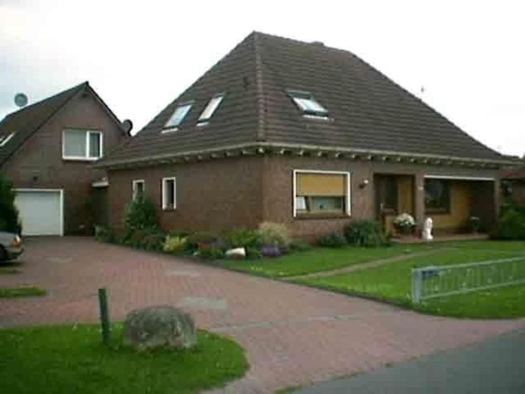 uma casa de tijolos com um cão na entrada em Wohnung in Wilhelmsfehn mit Terrasse, Garten und Grill em Wiesmoor