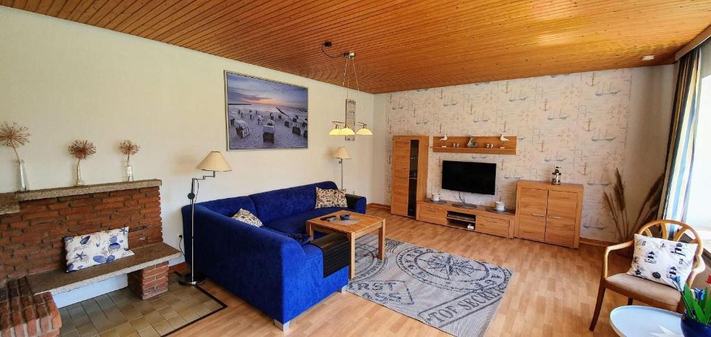 ein Wohnzimmer mit einem blauen Sofa und einem TV in der Unterkunft Ferienwohnung Floppy Hansi Fewo 4 EG in Sankt Peter-Ording