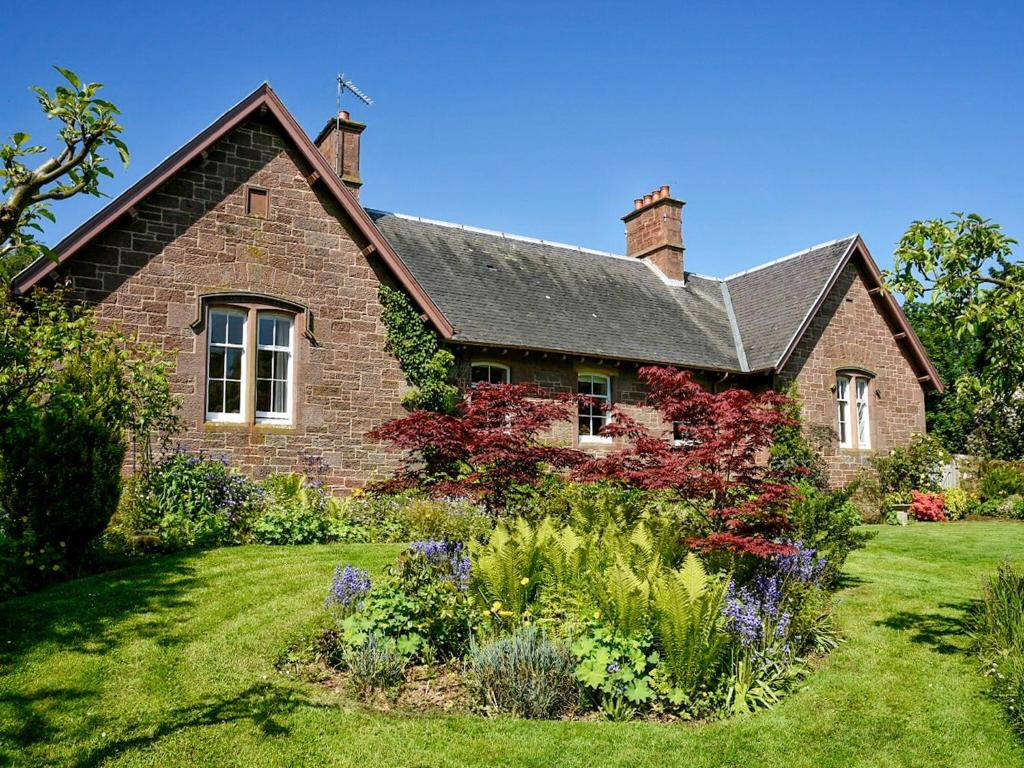 una casa in mattoni con giardino di fronte di Shepherds Cottage a Stenton