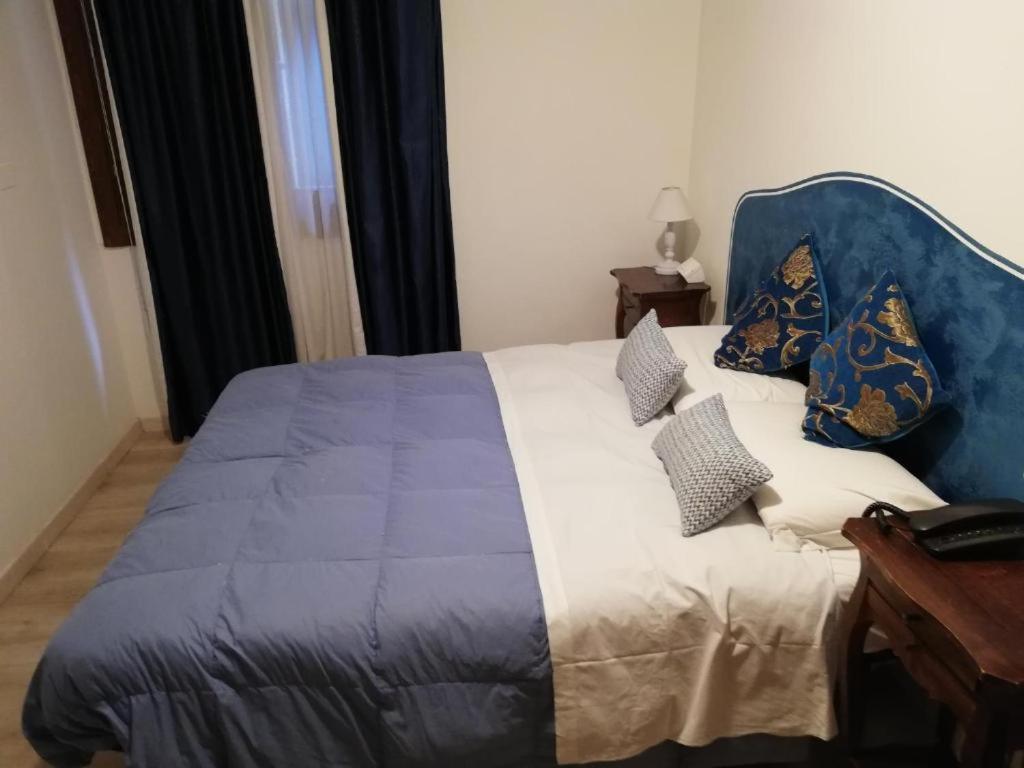 ein Schlafzimmer mit einem blauen Bett mit Kissen darauf in der Unterkunft Palazzo Lion Morosini - Check in presso Locanda Ai Santi Apostoli in Venedig