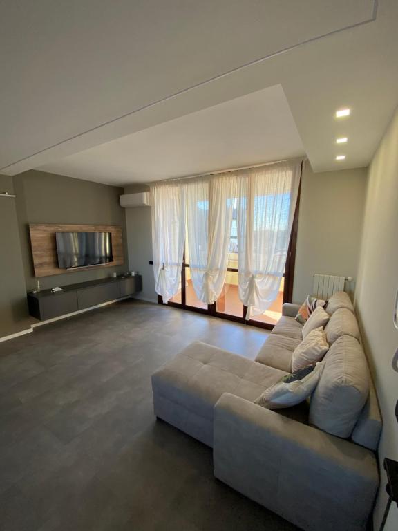 a large living room with a couch and two windows at La Casa di Davide Milano Monza in Concorezzo