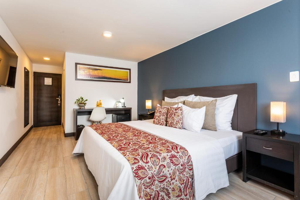 een slaapkamer met een groot bed met witte lakens bij Hotel Carretero in Manizales