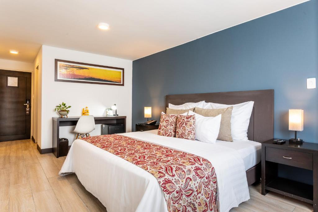 a bedroom with a large bed with white sheets and pillows at Hotel Carretero in Manizales