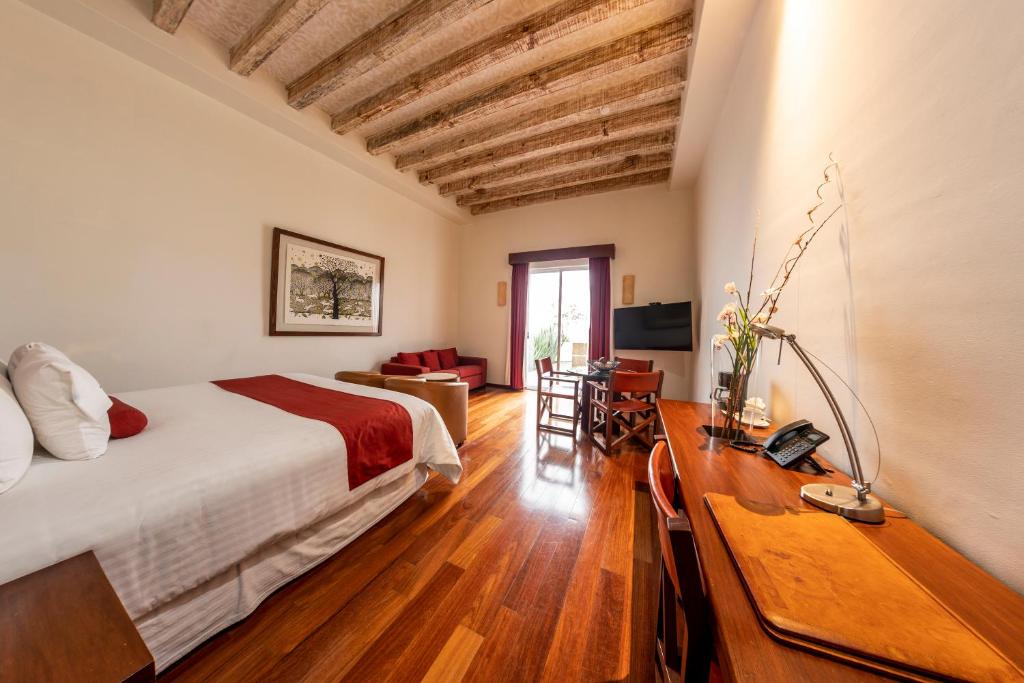 een slaapkamer met een bed, een bureau en een bank bij Hotel Boutique Casa San Diego in Morelia