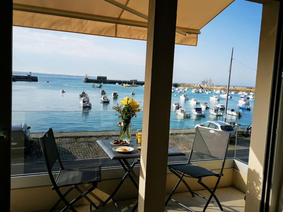 un balcone con tavolo, sedie e barche in acqua di Charme et zénitude, avec vue exceptionnelle sur le port a Granville