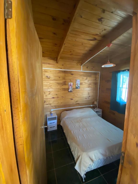 1 dormitorio con 1 cama en una cabaña de madera en Tadekim, en Punta del Diablo